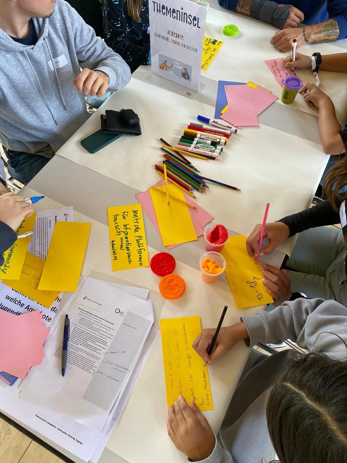 kinder sitzen an einem tisch und schreiben