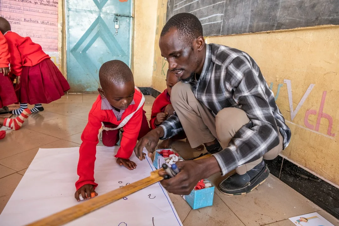 lehrer sitzt mit schüler am boden und unterrichtet